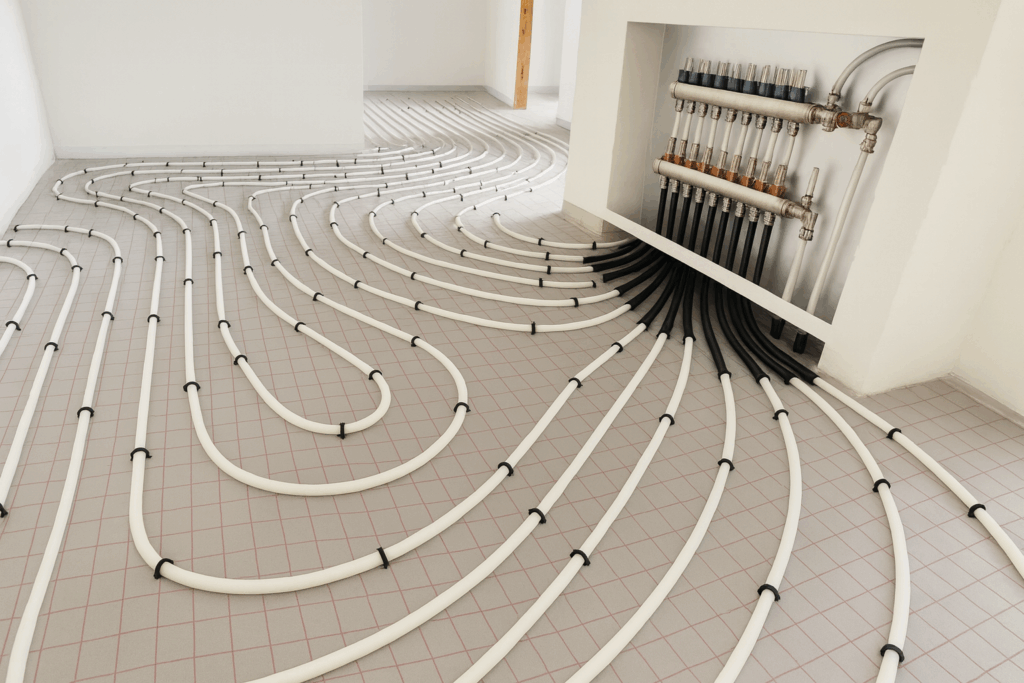 Radiant in-floor heating system installation by custom home builders in Edmonton, showing white tubing layout connected to a wall-mounted manifold